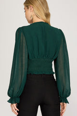 Back view of  woman wearing a green blouse with balloon sleeves with black pants 