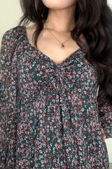 Close up of woman wearing a green floral mini dress with a sweetheart neckline